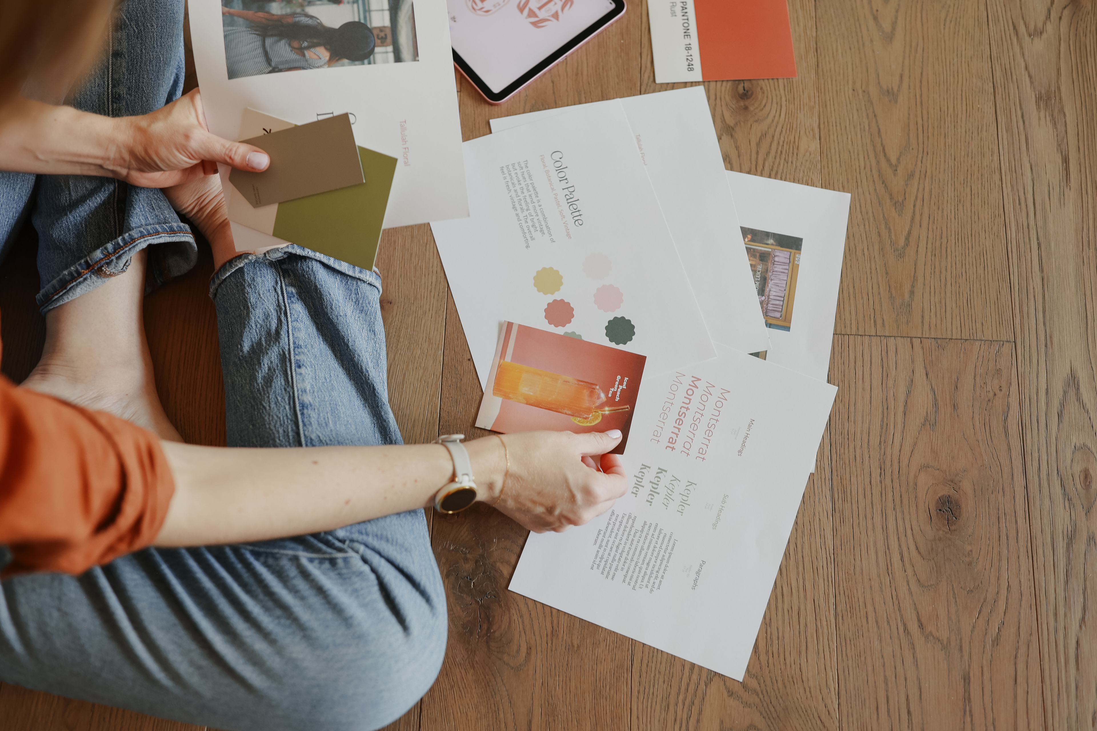 Person sitting on a wooden floor with various printed materials and cards for O Hey Amy Design Studio